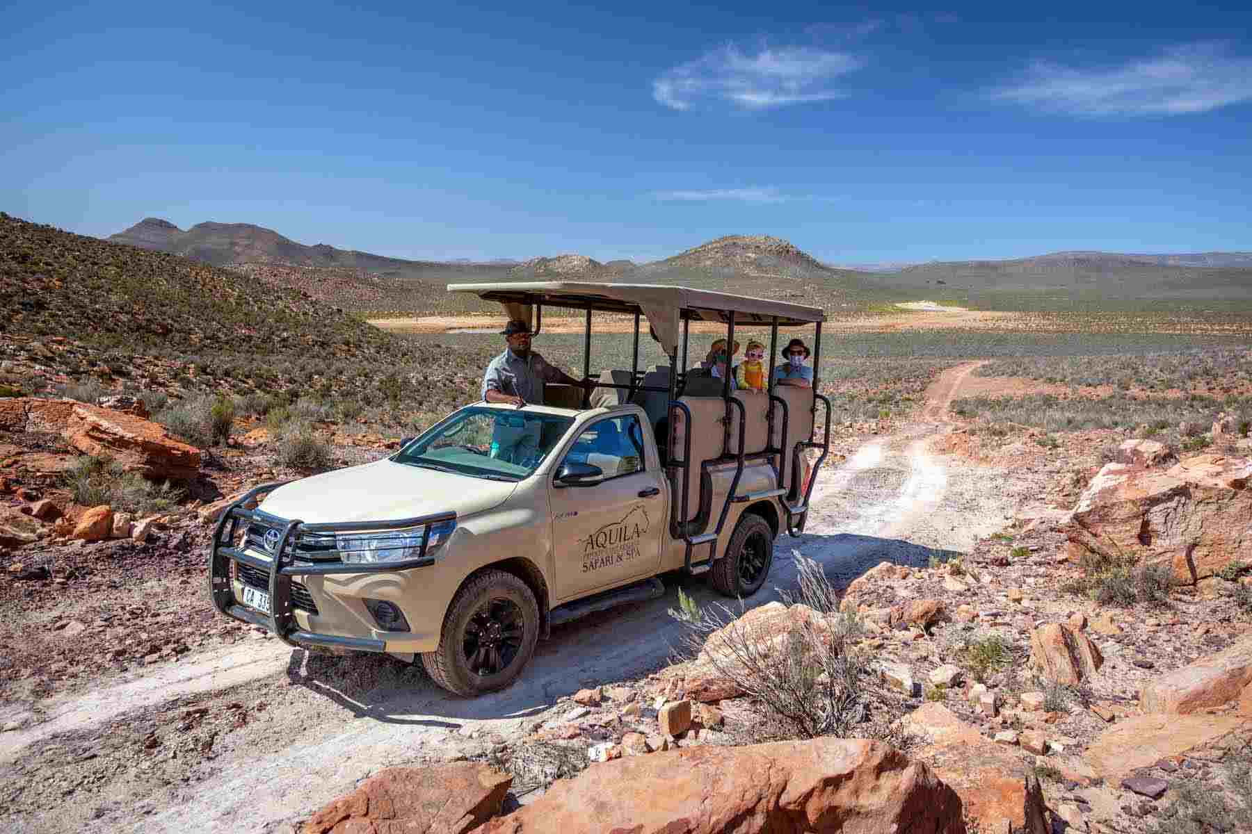 aquila private drive vehicle driving along a rocky Karoo dirt road, shown as part of Aquila's "about us" initiative.