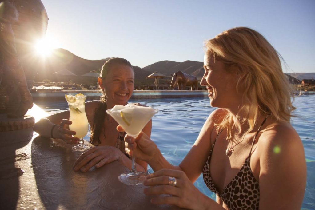 two women enjoying cocktails at Aquila's infinity pool wet bar — the best Cape Town safari experience