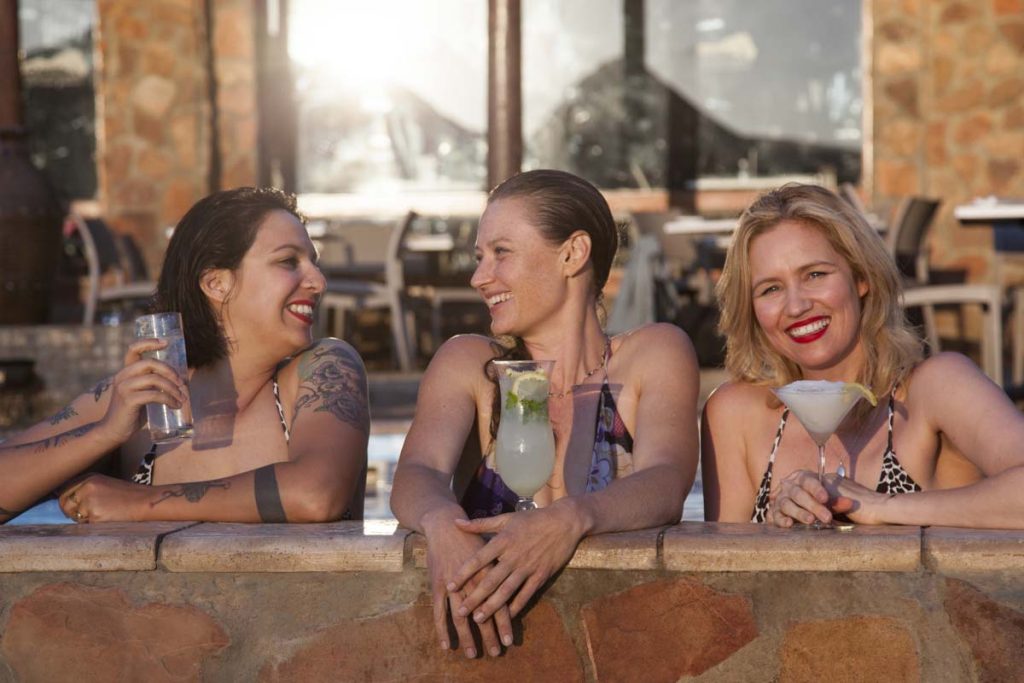 three women holding cocktails in the pool while enjoying the convenience of Aquila's wet bar.