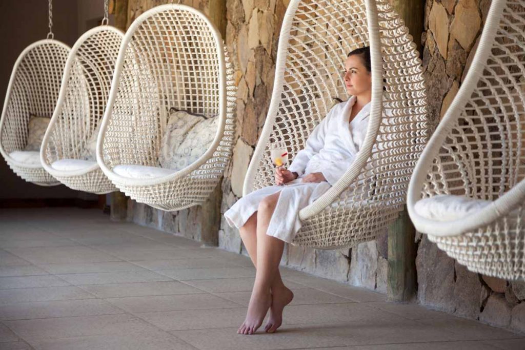 woman in a bathrobe holding a drink and sitting in Tranquila Spa, enjoying a rejuvenating wellness retreat inspired by nature and the Karoo.
