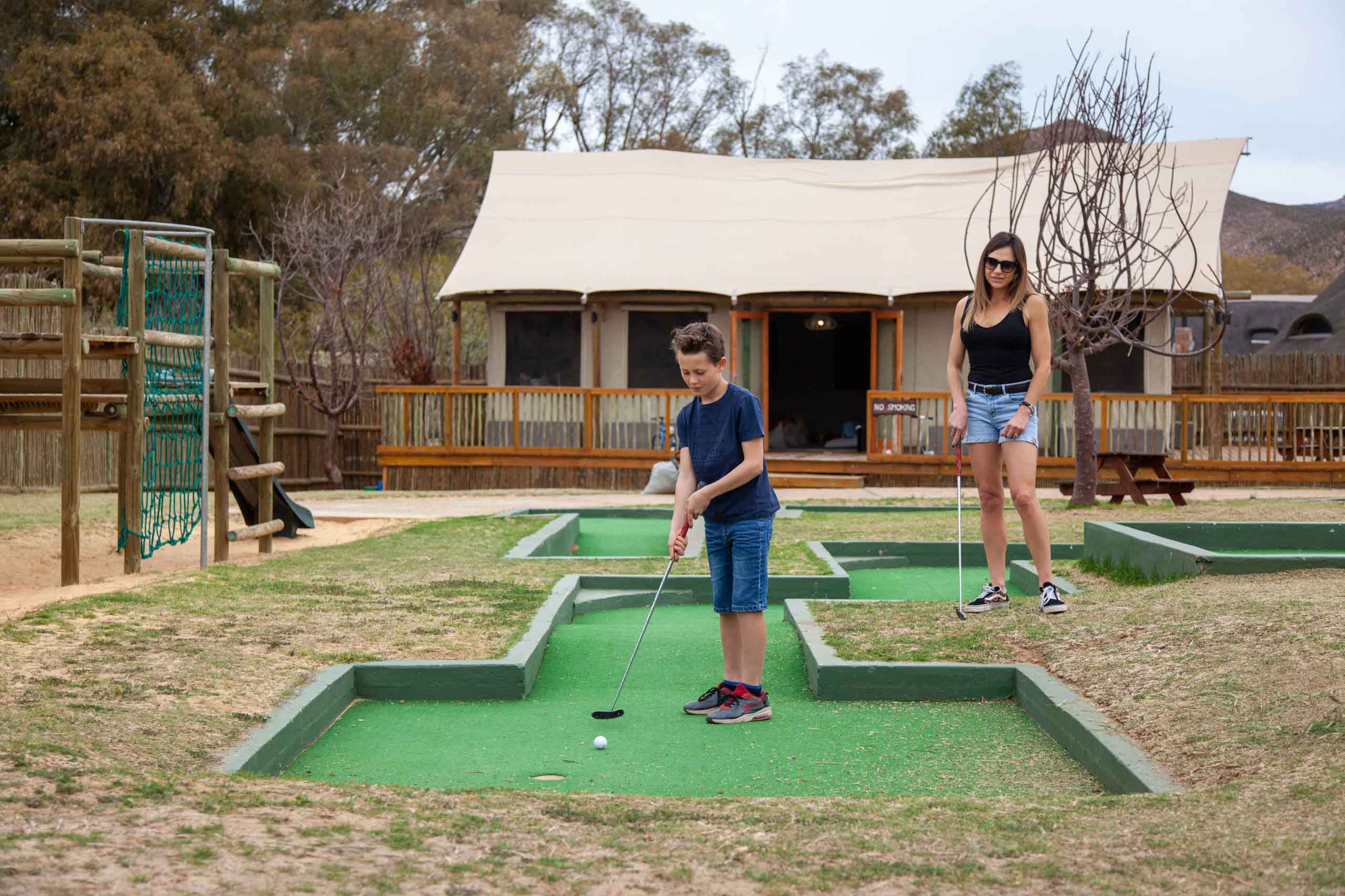 Child playing on Aquila's mini golf course, situated in the Children Entertainment Area and Kids Adventure Zone.