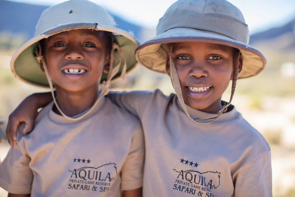 Two children wearing safari hats are smiling as they partake in Aquila Safari's Junior Ranger Programme