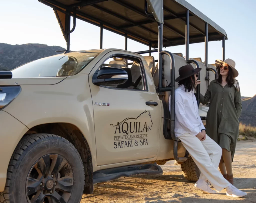 Couple leaning against an Aquila Safari vehicle as part of our big 5 booking guide